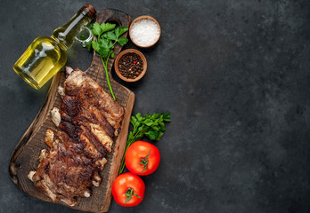 pork ribs with spices, tomatoes and herbs on a stone background with copy space for your text