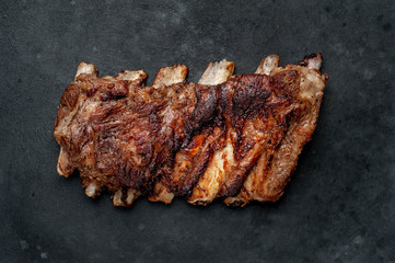 pork ribs with spices, tomatoes and herbs on a stone background