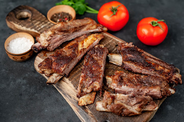pork ribs with spices, tomatoes and herbs on a stone background