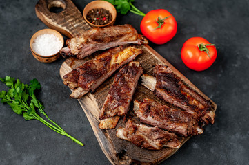pork ribs with spices, tomatoes and herbs on a stone background