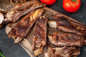 pork ribs with spices, tomatoes and herbs on a stone background