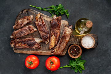 pork ribs with spices, tomatoes and herbs on a stone background
