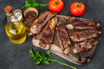 pork ribs with spices, tomatoes and herbs on a stone background