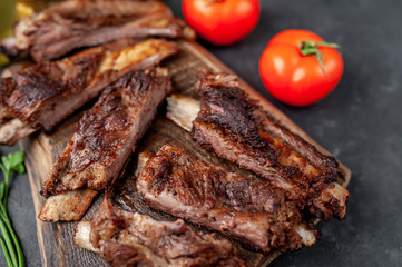 pork ribs with spices, tomatoes and herbs on a stone background