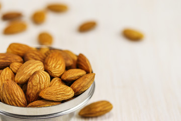 Almonds in a metal bowl and on a white surface