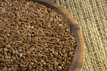 Obraz premium Flax seeds in a wooden plate, closeup. Natural healthy food for diet. Raw material for linseed oil.