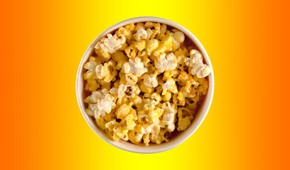 Glass bowl with salted popcorn on yellow background. Top view with copy space.