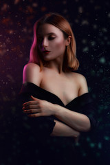 Obraz na płótnie Canvas Close up luxury portrait of young romantic woman with long blonde hair in black dress, bare, shoulder on a dark colorful neon light background. Contrasting pink light
