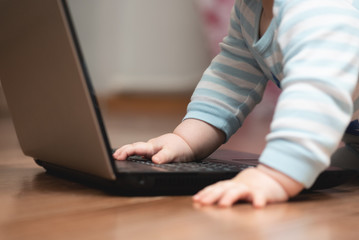 Baby is studying a laptop on the floor close up.