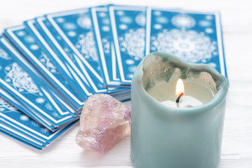 Blue tarot cards deck and burning candle close up.