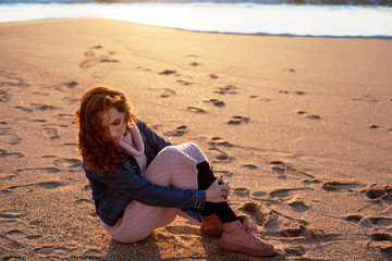 Pretty woman walking on the sand beach, the wind blowing hair of the model. Woman enjoing the waves on the ocean and breathing fresh air at sunset