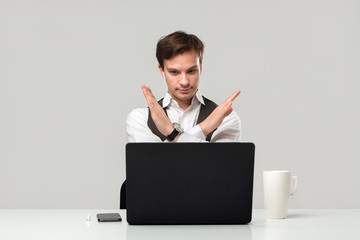 Businessman in a white t-shirt and grey vest is shocked checking information on a laptop