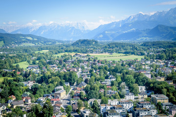 Fototapeta na wymiar Houses surrounded with trees in the Salzach river valley below the mountains 