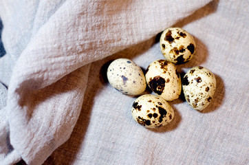 A few bright quail eggs lie on a gray linen napkin. Preparing to paint eggs for Easter. Selective...