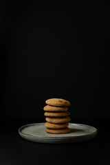 Stack of oatmeal cookies on a clay plate on black background. Isolate