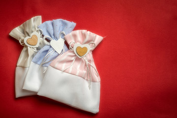 Three rag gift bags with a heart and a bow on a red faded background, top view with copy space. Holiday concept.