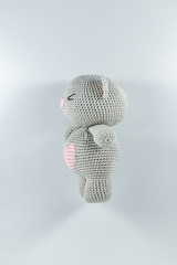 a small knitted toy grey bear cub with a pink heart on its belly