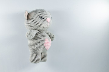 a small knitted toy grey bear cub with a pink heart on its belly