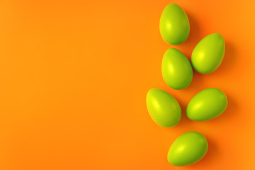 Simple compositon with green Easter eggs on vivid orange background