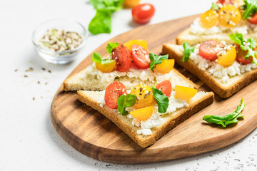 Cherry tomatoes goat cheese toasts. Selective focus, copy space.