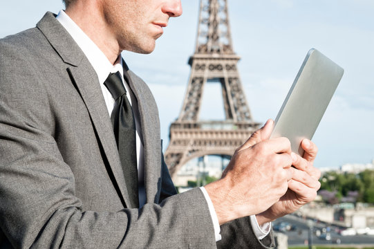 European businessman using digital tablet computer outdoors in front of the Eiffel Tower in Paris France
