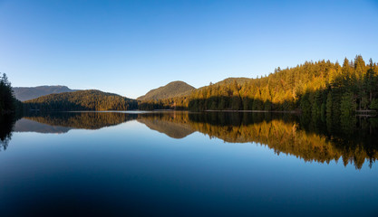 Beautiful and Vibrant panoramic view of a lake surounded by Canadian Mountain Landscape during sunset. Taken in White Pine Beach, Port Moody, Vancouver, British Columbia, Canada. Panorama