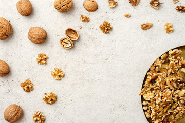 Whole and cracked walnuts, copy space in the middle on grey background. Flat lay, top view.