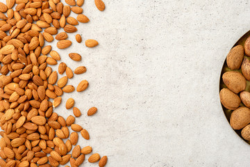 Whole and cracked organic almonds  on grey background. Flat lay, top view, copy space.