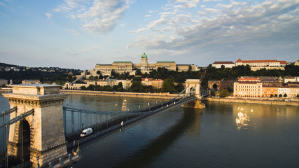 Fototapeta premium Drone view of Szechenyi Chain Bridge, Clark Adam Square. Buda Castle Royal Palace and Buda Tunnel at sunrise on a summer morning. Buda castle in the background.