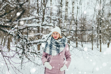 Fototapeta na wymiar Beautiful winter view with snowfall - young attractive blonde outdoors in the frost - portrait of young caucasian woman