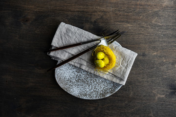 Festive table setting for holiday Easter dinner decorated with eggs and boxwood on stone background with copy space