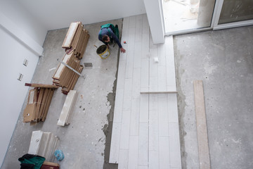 worker installing the ceramic wood effect tiles on the floor