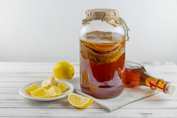Kombucha superfood pro biotic tea fungus beverage in glass bottle and jar with lemon on white background