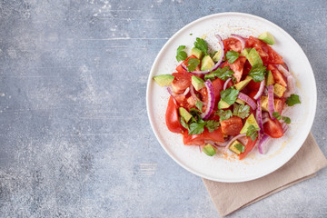 Vegetables salad with tomatoes, avocado and red onion. Top view with copy space