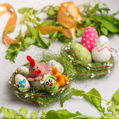 Fototapeta na wymiar decorative colored Ester chicken, bunnys and eggs on straw against the background of decorative colored eggs made of wool