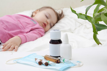 Obraz na płótnie Canvas Medicines and ampoules on the background of a sleeping child. Toddler treatment concept
