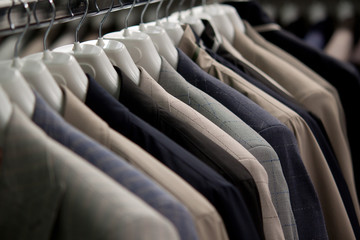classic men's woolen jackets of different colors hang on a hanger in a store