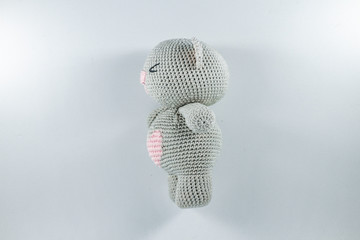 a small knitted toy grey bear cub with a pink heart on its belly
