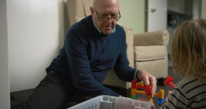 Grandfather and grandchild playing with marble run at home