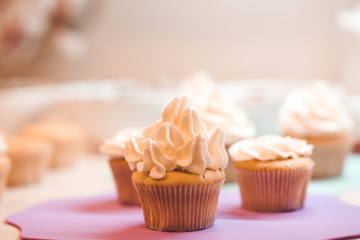 Cup cake with cream cheese on kitchen table closeup.
