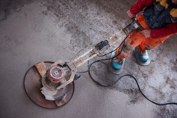 worker performing and polishing sand and cement screed floor