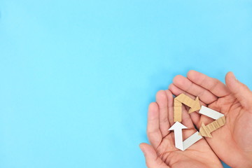 Cupped hands holding a recycling symbol in blue background. Recycled cardboard paper material.