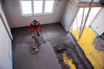 worker performing and polishing sand and cement screed floor
