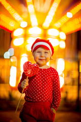 Little girl in red clothes and cap eats candy