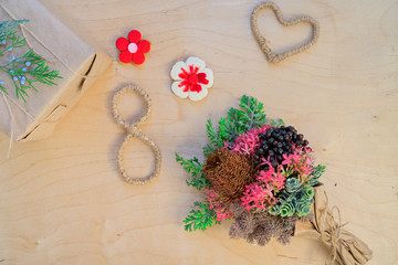 Happy Women's Day. Background for Women's Day. Greeting card international women's day March 8. Gift box made of Kraft paper and a bouquet on a wooden background