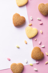 Heart shaped cookies and colorful sprinkles with shirt of paper, copy space for text. Pink paper background. Love concept, 8 March, International Happy Women's Day, Birthday.