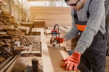 Young man carpenter at the wooden workshop
