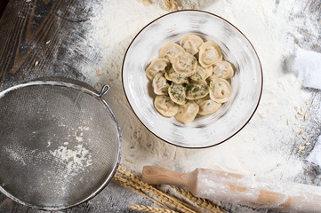 Russian traditional pelmeni with meat on a white plate. Wheat spikes, on a wooden board