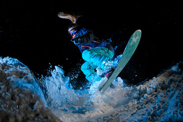 Woman snowboarder doing stunts on blue light background