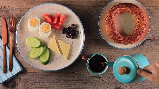 top view of Pouring turkish tea into the cup with teapot and turkish simit on the table